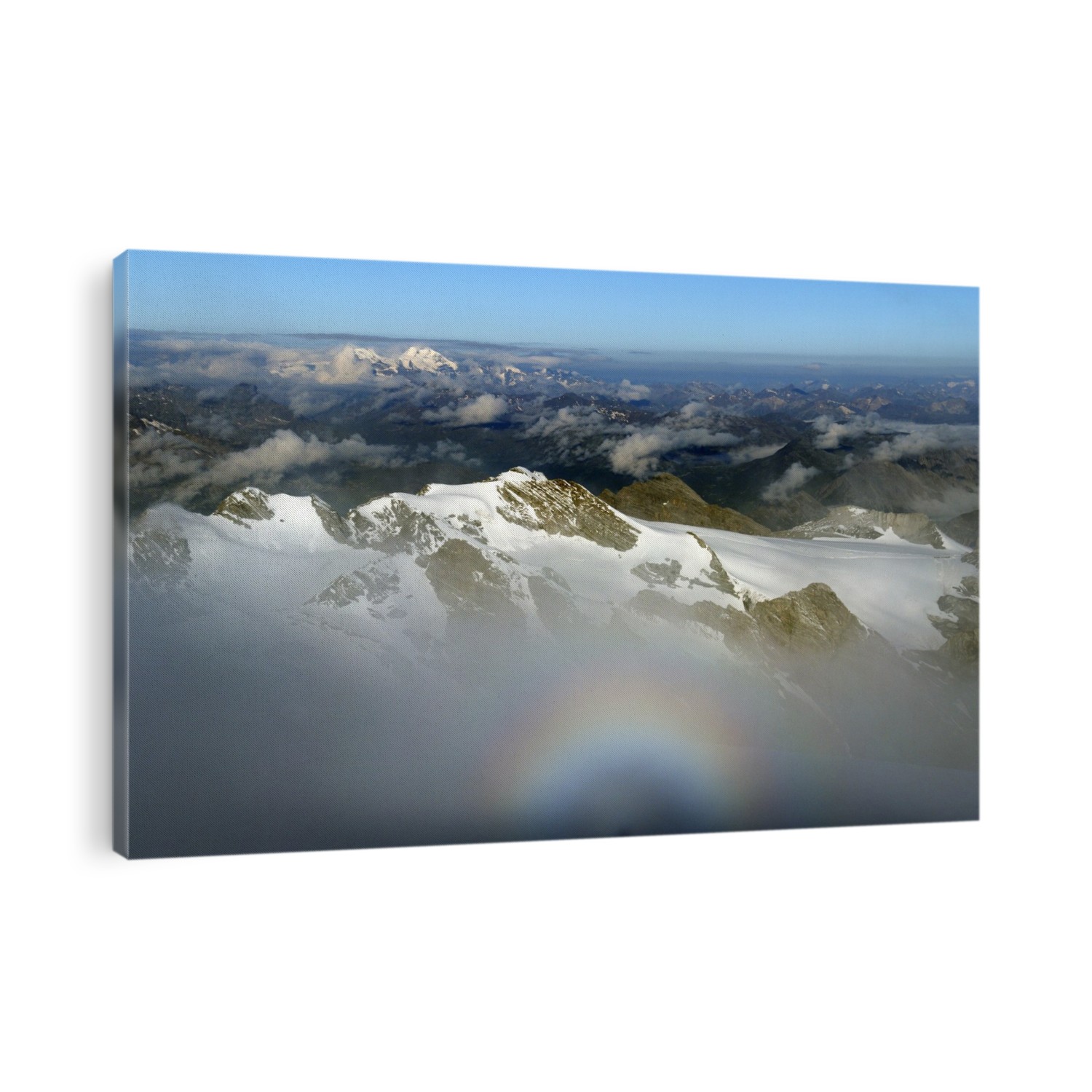 Italian-Swiss Alps. View looking west from the summit of Mount Ortler (3905 metres) towards the peaks of the Bernina Range. The highest peak in that range, Piz Bernina (4049 metres) is in the distance at upper left. The rainbow-like feature in the fog at bottom is an aureole. Photographed in August.